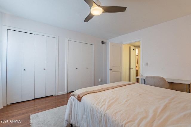 bedroom with two closets, ceiling fan, and hardwood / wood-style flooring