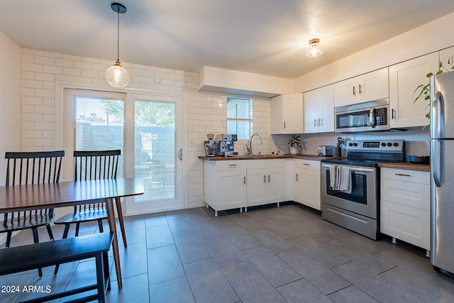 kitchen featuring pendant lighting, stainless steel appliances, sink, and white cabinetry