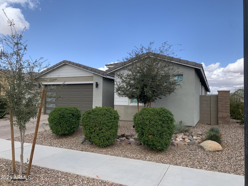 view of side of home featuring a garage, a tile roof, driveway, and stucco siding