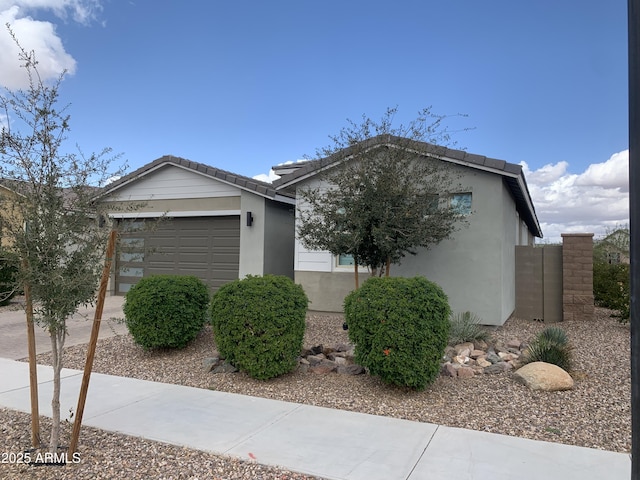 view of side of home featuring a garage, a tile roof, driveway, and stucco siding