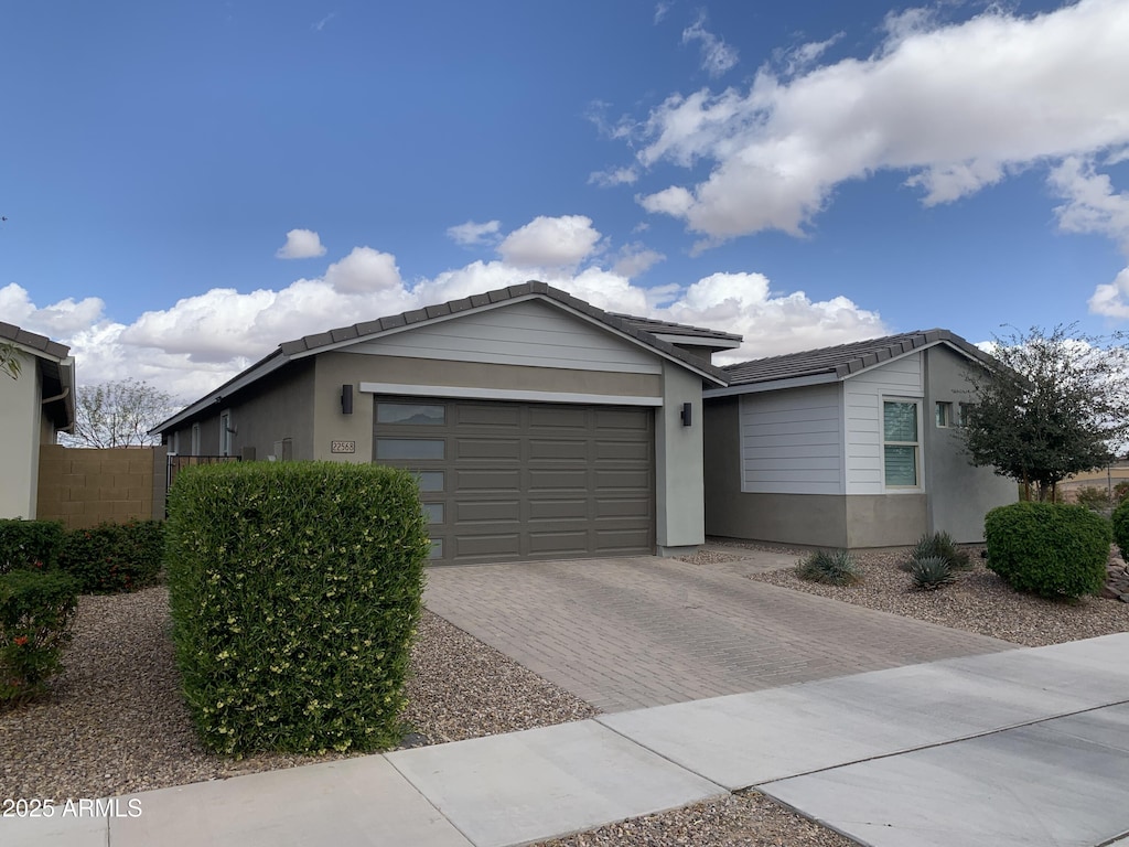 ranch-style house featuring a garage, fence, decorative driveway, and stucco siding