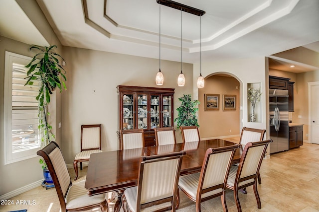 dining area featuring a raised ceiling and light tile floors