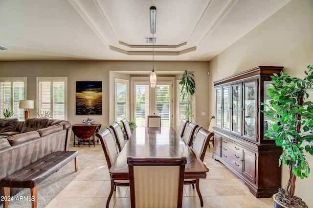 dining room featuring a tray ceiling and light tile flooring