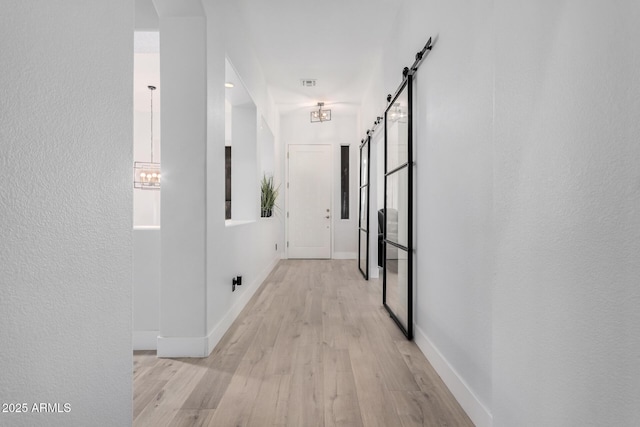 corridor featuring a barn door and light hardwood / wood-style flooring