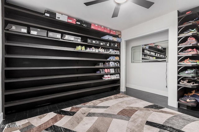 spacious closet with dark wood-type flooring and ceiling fan