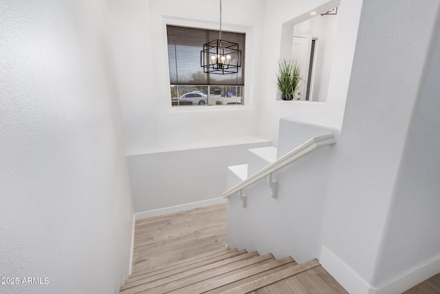 staircase featuring wood-type flooring and a chandelier