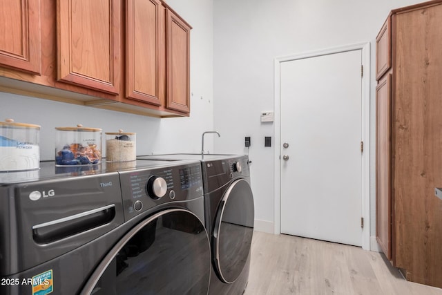 washroom featuring cabinets, washing machine and dryer, and light wood-type flooring