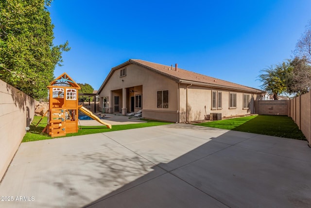 rear view of property with a yard, a patio, and a playground