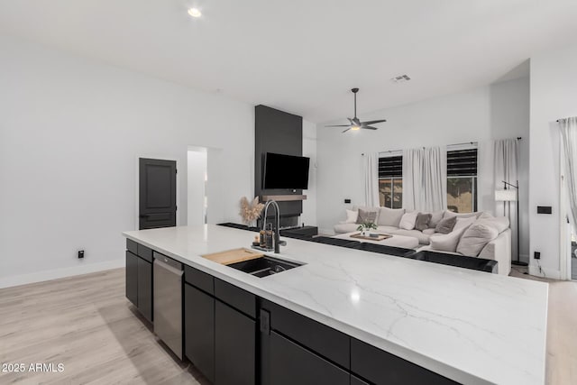 kitchen featuring dishwasher, sink, ceiling fan, light hardwood / wood-style floors, and light stone countertops