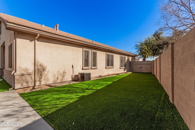 back of property with central AC unit and a lawn