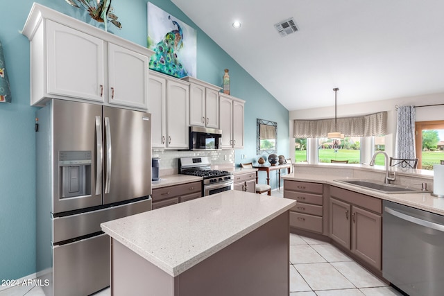 kitchen with tasteful backsplash, sink, hanging light fixtures, a kitchen island, and appliances with stainless steel finishes