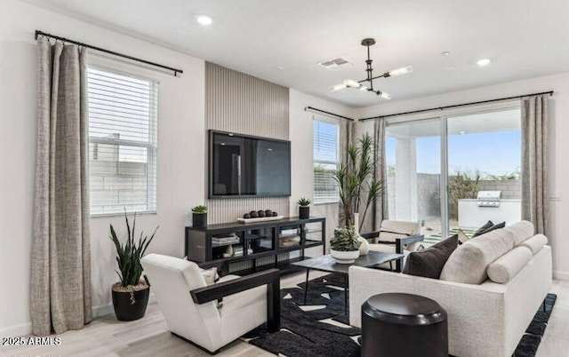 living area with light wood-style floors, visible vents, a notable chandelier, and recessed lighting