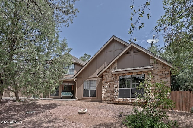 rear view of house with stone siding and fence