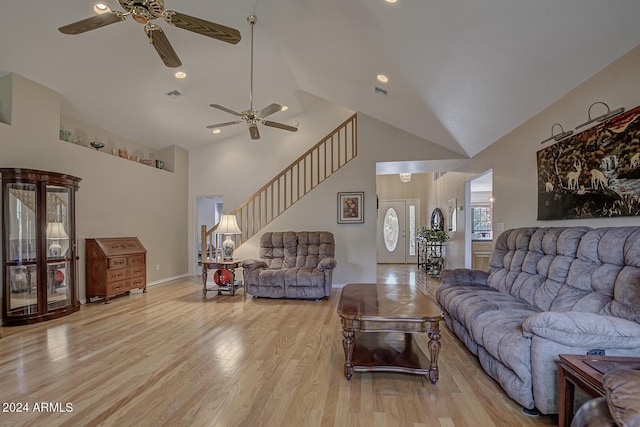 living area with high vaulted ceiling, visible vents, stairway, and light wood finished floors