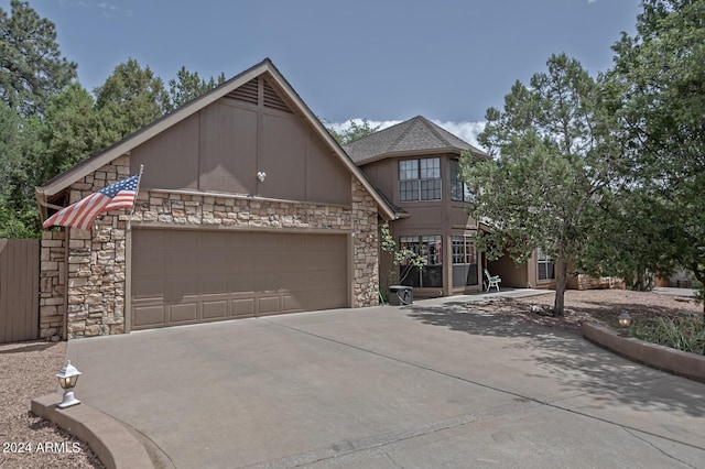 view of front facade with an attached garage, stone siding, and concrete driveway