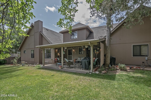 rear view of property with a yard, a patio, and roof with shingles