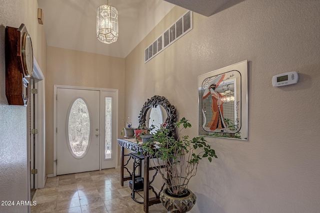 entryway with a chandelier, a high ceiling, and visible vents