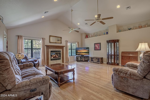 living room featuring high vaulted ceiling, visible vents, a fireplace, and light wood-style flooring