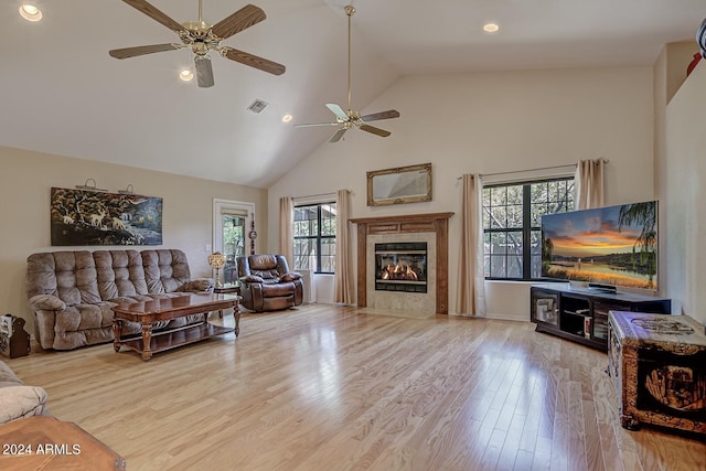 living area with recessed lighting, visible vents, high vaulted ceiling, light wood-type flooring, and a tile fireplace