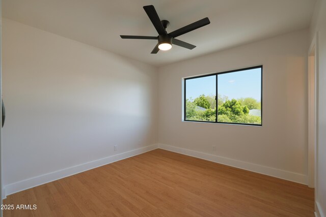 spare room featuring light wood finished floors, baseboards, and ceiling fan