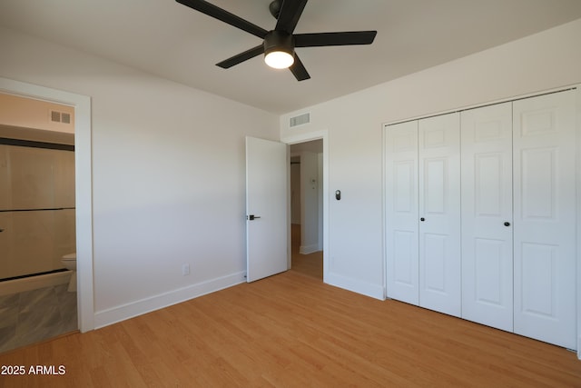 unfurnished bedroom featuring baseboards, light wood-type flooring, a closet, and ensuite bathroom