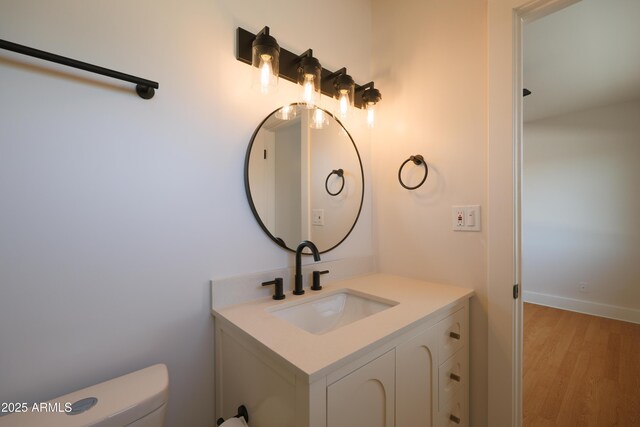 bathroom with wood finished floors, vanity, toilet, and baseboards