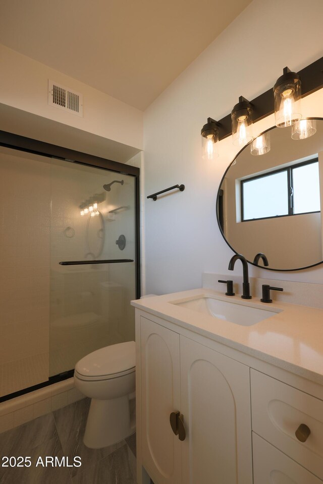 bathroom with toilet, a shower stall, and vanity