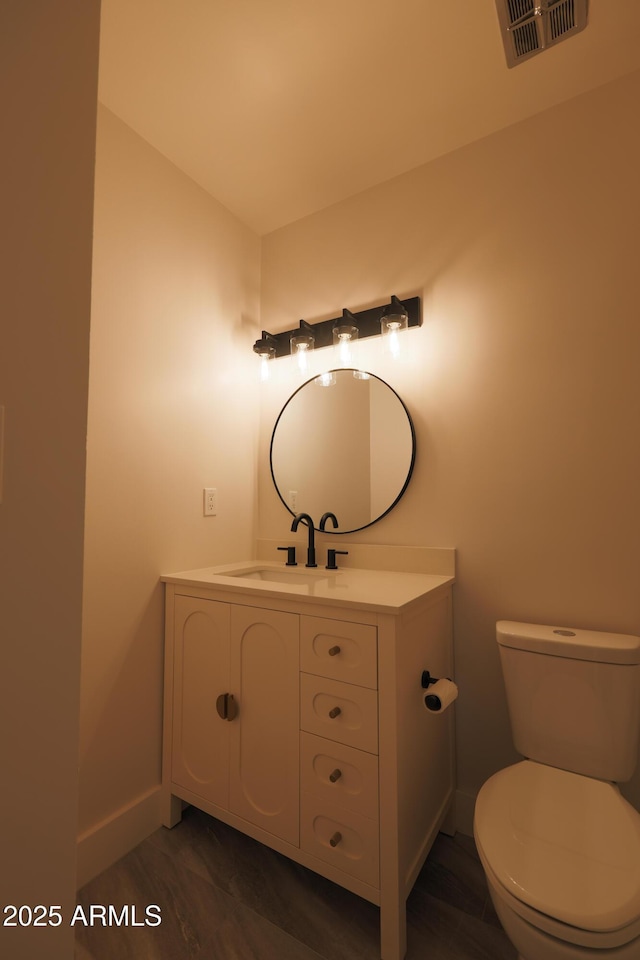 half bathroom with toilet, vanity, and baseboards