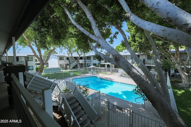 community pool with fence, a patio, and a residential view