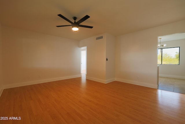 unfurnished room featuring light wood-style flooring, baseboards, a chandelier, and a ceiling fan