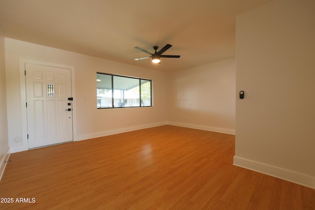 spare room with light wood-type flooring, ceiling fan, and baseboards