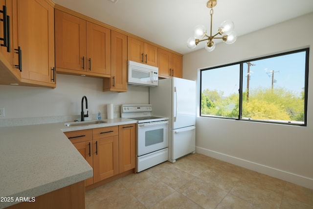 kitchen featuring white appliances, a sink, a chandelier, decorative light fixtures, and baseboards