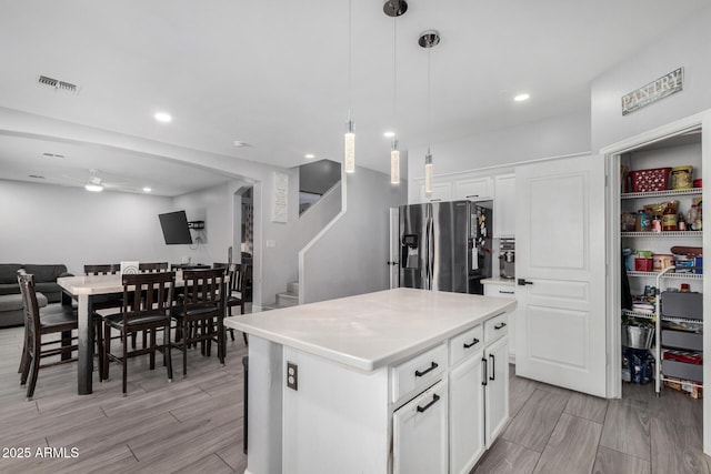 23848 W Grove St, Buckeye, AZ 85326 - kitchen with white cabinets, visible vents, a kitchen island, stainless steel fridge, and open floor plan
