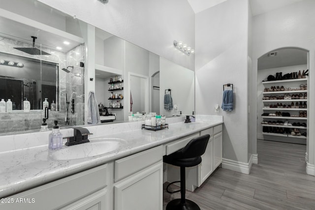 23848 W Grove St, Buckeye, AZ 85326 - full bathroom with baseboards, a sink, double vanity, wood finished floors, and a marble finish shower