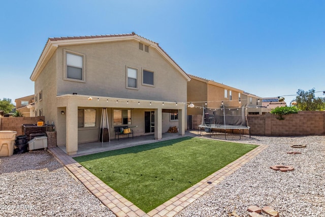 23848 W Grove St, Buckeye, AZ 85326 - rear view of house with a trampoline, stucco siding, fence, and a lawn