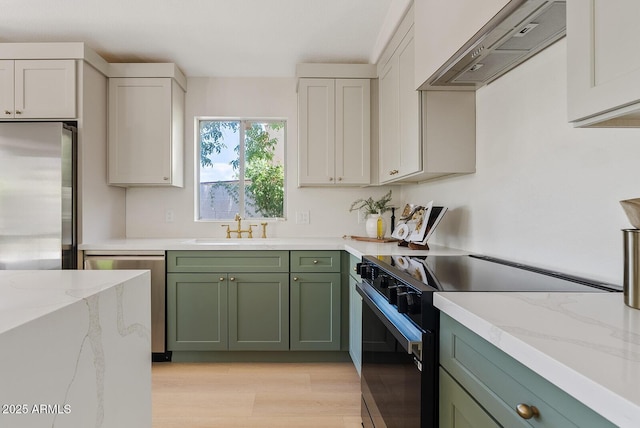 732 W Sagebrush St, Gilbert, AZ 85233 - kitchen featuring green cabinets, stainless steel appliances, wall chimney exhaust hood, a sink, and light wood-style flooring