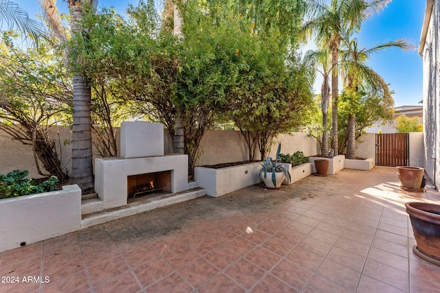 7385 E Pleasant Run, Scottsdale, AZ 85258 - fenced backyard featuring a lit fireplace, a patio area, and a gate
