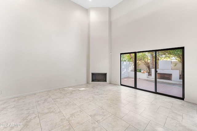 7385 E Pleasant Run, Scottsdale, AZ 85258 - unfurnished living room featuring a towering ceiling, a fireplace, and tile patterned flooring