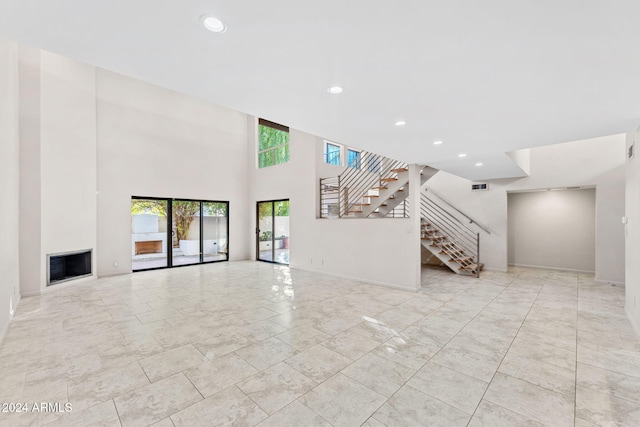 7385 E Pleasant Run, Scottsdale, AZ 85258 - unfurnished living room with stairs, recessed lighting, a fireplace, and a towering ceiling