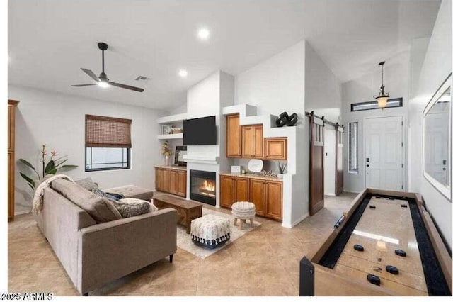 tiled living room featuring a barn door, ceiling fan, built in features, and high vaulted ceiling