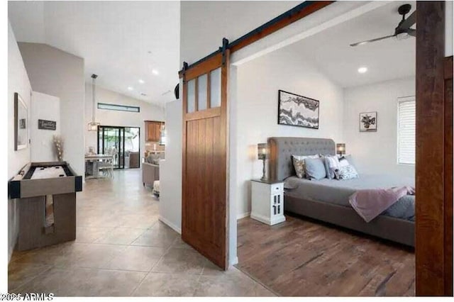 bedroom featuring tile patterned floors, ceiling fan, a barn door, and high vaulted ceiling