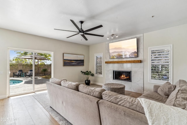 living room featuring a tiled fireplace and ceiling fan