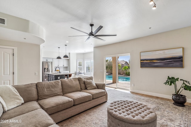 living room featuring light hardwood / wood-style flooring, ceiling fan, and sink