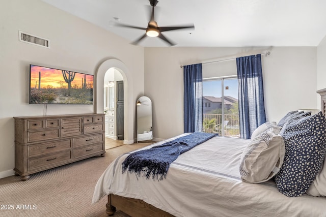 bedroom featuring ceiling fan, connected bathroom, vaulted ceiling, and light colored carpet