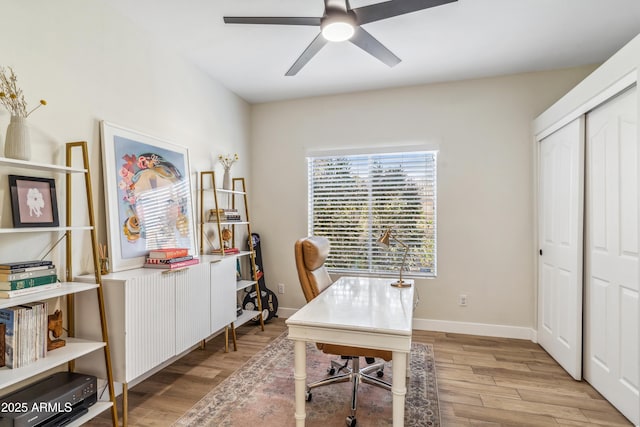 home office with light hardwood / wood-style floors and ceiling fan