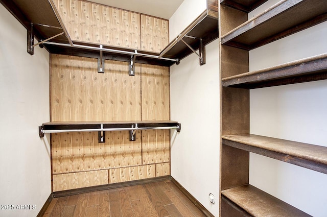 spacious closet featuring dark wood finished floors and built in desk