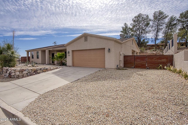 view of front facade with a garage, fence, concrete driveway, and stucco siding