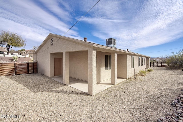 back of property featuring central AC unit, a patio area, fence, and stucco siding