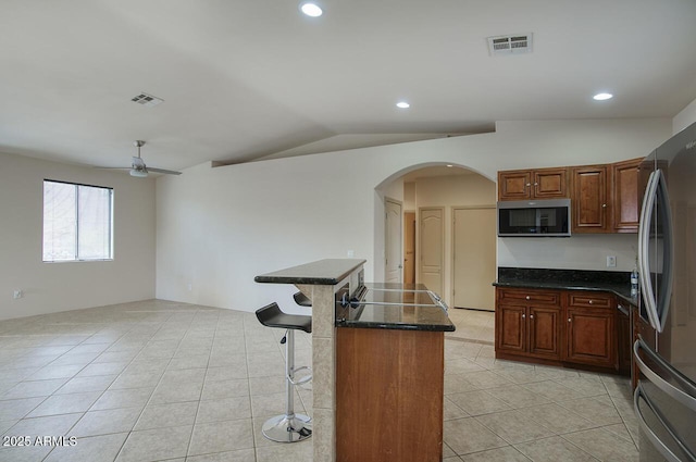 kitchen featuring visible vents, a kitchen breakfast bar, vaulted ceiling, appliances with stainless steel finishes, and a center island