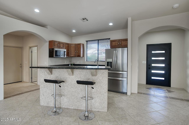 kitchen featuring recessed lighting, a breakfast bar, a kitchen island, appliances with stainless steel finishes, and dark countertops